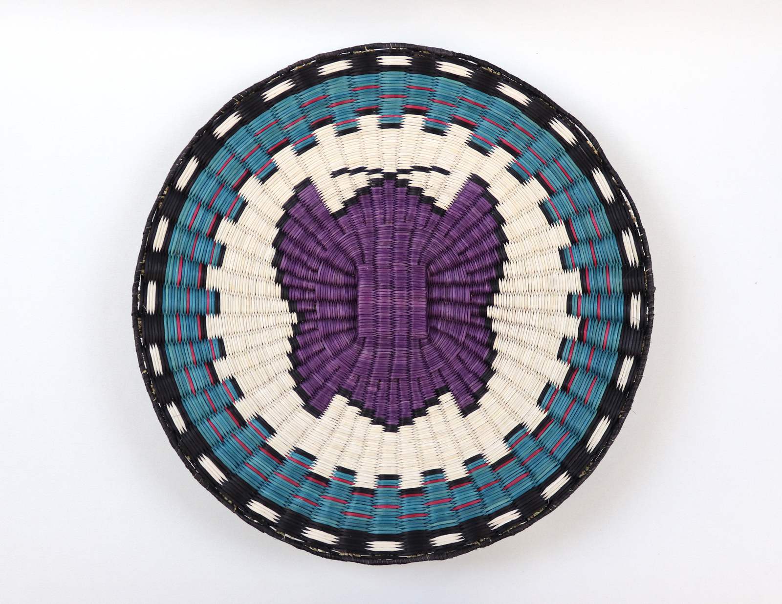Jessica Lomatewama, “Wicker Plaque with Butterfly,” a round woven plaque with a purple butterfly in the center